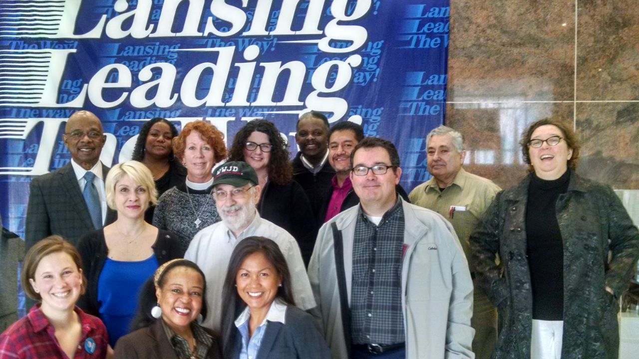 Brian Buehler in gray jacket with members of Action of Greater Lansing