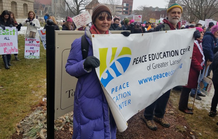 Becky Payne and Terry Link holding Peace Education Center banner at a demonstration.