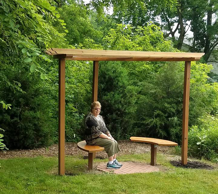 Woman sitting under trellis behind meetinghouse